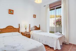 two beds in a room with a window at Casa Villanueva 2 - Sólo Familias in Conil de la Frontera +19 photos