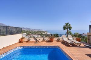 a swimming pool with two lounge chairs and the ocean at Balcon Bella Vista in Nerja