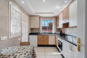 a kitchen with white cabinets and a table in it at terrazas del duque fase2 in Adeje