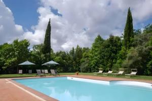 a swimming pool in a garden with chairs and umbrellas at Rosaspina - Appartamento 6 in Capalbio