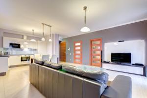 a living room with a large couch and a kitchen at Apartament Koga Waterlane in Gdańsk