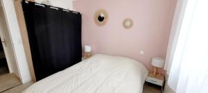 a bedroom with a bed with a black curtain and two mirrors at L'appartement De La Forêt in La Tranche-sur-Mer