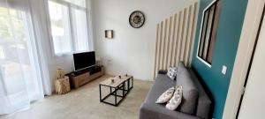 a living room with a couch and a tv at L'appartement De La Forêt in La Tranche-sur-Mer
