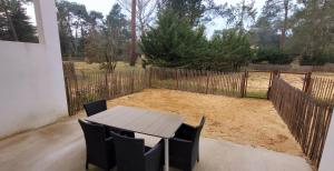 a wooden table and chairs in a yard with a fence at L'appartement De La Forêt in La Tranche-sur-Mer
