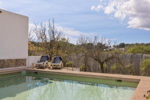 two chairs sitting next to a swimming pool at Finca Can Paci in Santa Eularia des Riu