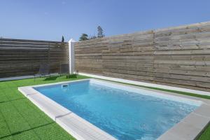 ein Swimmingpool in einem Garten neben einer Holzmauer in der Unterkunft Casa Sofia in Roche