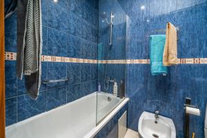 a blue tiled bathroom with a tub and a toilet at Apartamento Belmar in Armação de Pêra