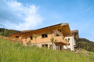 a large building on top of a grassy hill at Ratscheinerhof App Waldruhe in Lazfons