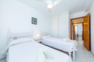 two beds in a white room with white sheets at Apartment La Veleta with Sea View in El Port +20 photos