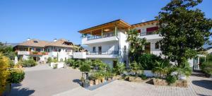 a large white building with a courtyard with plants at Peter Paul Domblick Erdgeschoss in Appiano sulla Strada del Vino