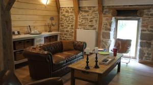 a living room with a leather couch and a table at La Trouverie in Laqueuille