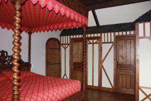 - une chambre avec un lit à baldaquin rouge dans l'établissement Au p'tit Mont, à Ardevon