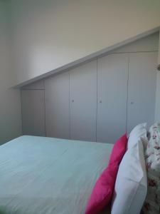 a white bed with pink and white pillows on it at Charmant appartement à Ainhoa in Ainhoa