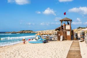 a beach with a gazebo and a boat on the sand at Finca Fiori 1 in Is Molas 