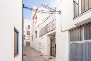 an alley between two white buildings at Cueva Del Gollisno in Chulilla