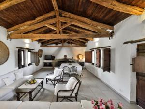a living room with white furniture and wooden ceilings at Finca Fiori 1 in Is Molas 