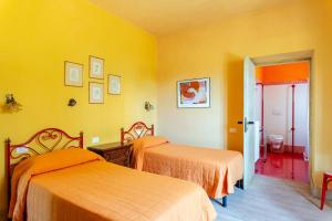 two beds in a room with yellow walls at Tramonto al Rifugio Arcobaleno in Popiglio