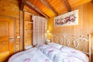 a bedroom with a bed in a wooden room at Orserose Chalet 8 I Fer Da Stir in Forno di Zoldo +4 photos