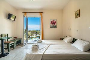 a hotel room with two beds and a balcony at Anemona studio D in Kefallonia