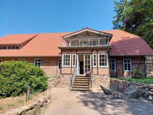 a brick house with a porch and chairs in front of it at Suite mit Wintergarten in Dedelstorf