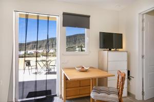 a room with a table and a television and a balcony at Fewo Arafo in Güimar