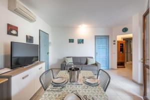 a living room with a table with chairs and a tv at Appartamento Isabel in Villasimius