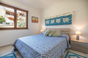 a bedroom with a blue bed and a window at Appartamento Isabel in Villasimius +25 photos