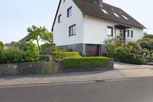 a white house with bushes in front of a street at Ferienwohnung en Verde in Felsberg