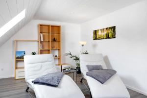 two white chairs and a table in a room at Ferienwohnung en Verde in Felsberg