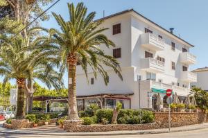 a white building with palm trees in front of it at La Cabanya Apartment 3d in Canyamel