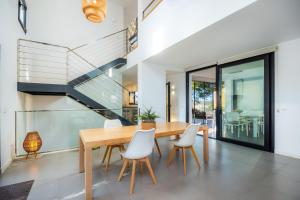 a dining room with a wooden table and white chairs at Es Nautic in Porto Cristo