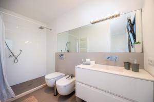 a white bathroom with a toilet and a mirror at Es Nautic in Porto Cristo +22 photos