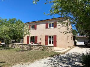 a large brick house with red shutters at Mas Les Coutilles in Cabrières-dʼAvignon