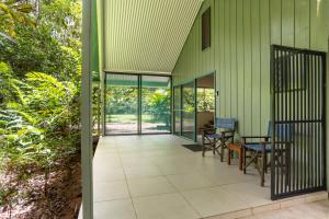 an external view of a green building with a patio at Harmony Creek - The Cottage in Cow Bay +14 photos