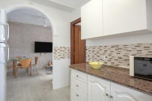 a kitchen with white cabinets and a dining room at Piso Río de Conil in Conil de la Frontera
