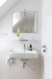 a white bathroom with a sink and a mirror at Strandroggen in Böhl