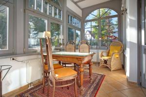 a dining room with a table and chairs and windows at Effi-Briest-Villa in Heringsdorf