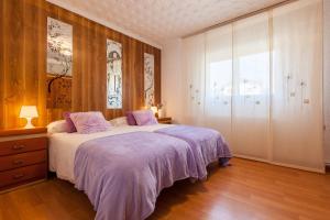 a bedroom with a bed with purple sheets and a window at Cal Ramon con piscina in Rubí +34 photos