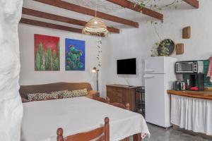 a kitchen and living room with a table and a refrigerator at Casa Cueva Rural, Calima in Juncalillo