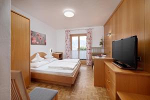 a hotel room with a bed and a flat screen tv at Humblhof in Lagundo