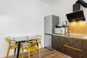 a kitchen with a table and yellow chairs and a refrigerator at Honey Home With Parking in Laives +15 photos
