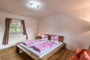 a bedroom with a bed with pink sheets and a window at Zuhaus am See in Gstadt am Chiemsee
