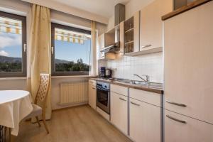 a kitchen with white cabinets and a table and a window at Residence Kronstein - Fewo 3 in Tesimo