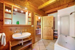 a bathroom with wooden walls and a sink and a tub at Ferienhaus Rauchegg - Bergblick in San Pancrazio dʼUltimo
