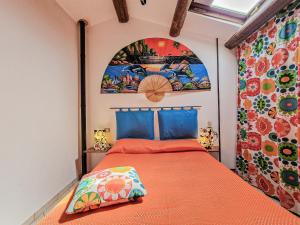 a bedroom with a orange bed with a painting on the wall at Il Borgo 4 in Capoliveri