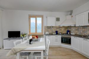 a kitchen with white cabinets and a table and chairs at Casa Doss in Tremosine Sul Garda