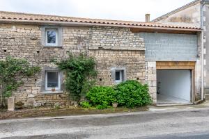 a stone house with a garage and aphaltphaltphalt at Studio proche Marais Poitevin in Oulmes