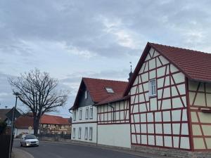 a white and black building with a car on a street at Thüringer Landidyll in Bösleben-Wüllersleben