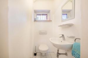 a white bathroom with a sink and a toilet at Haus Rose Muc City in Munich +18 photos