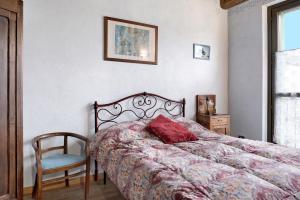 a bedroom with a bed with a red pillow and a chair at Casa Vacanze il Ginepro in Sinio